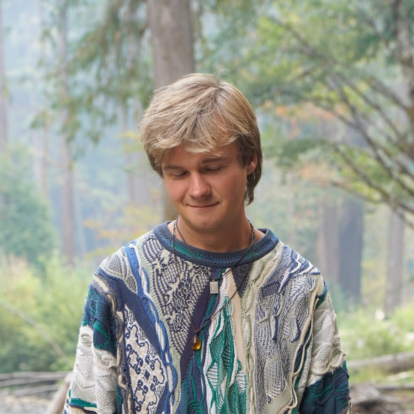 kyle wearing a patterned sweater in a forest setting