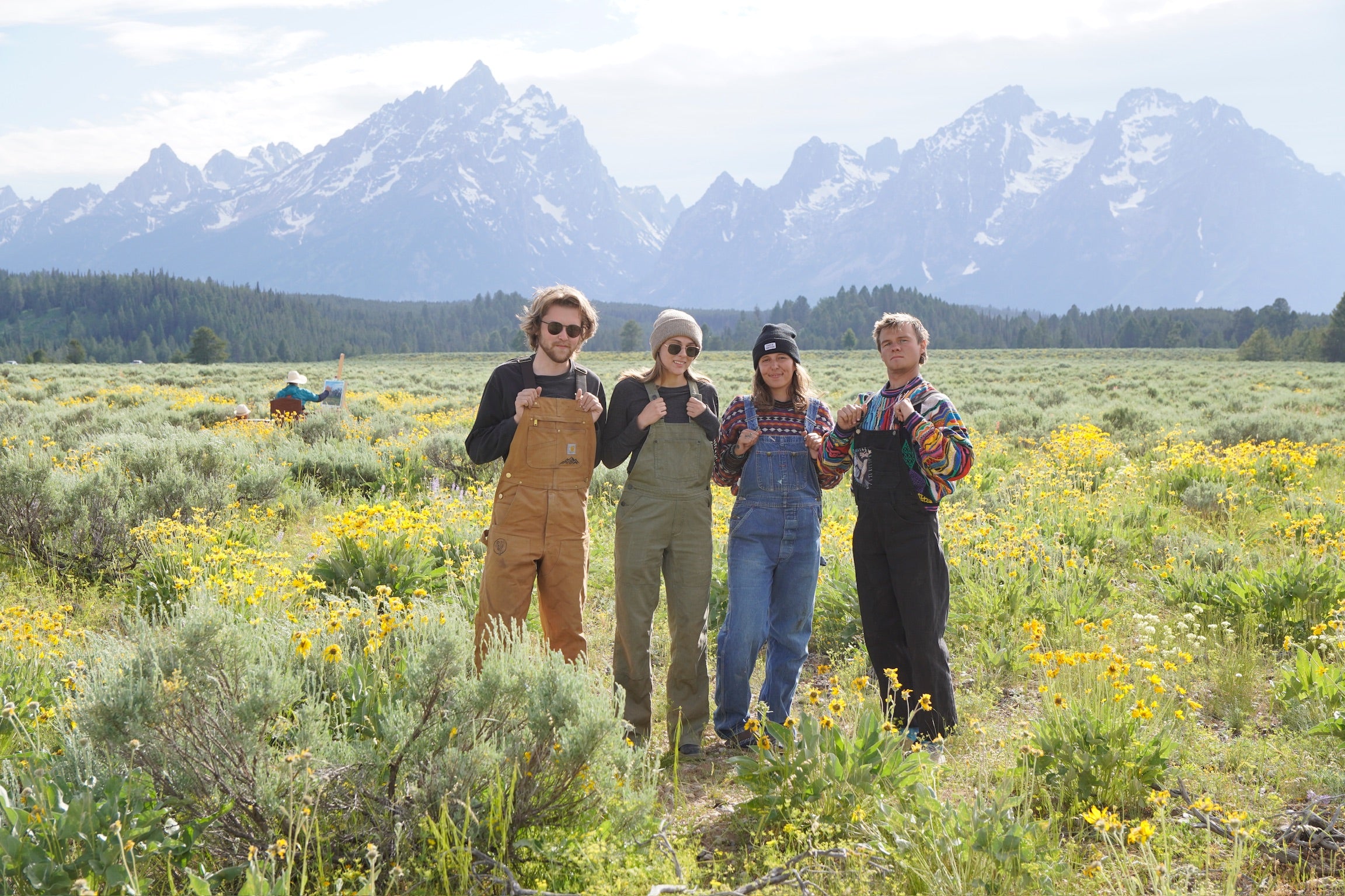 Four people standing in a field with mountains in the background